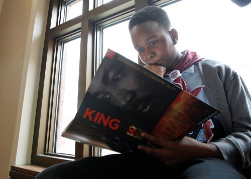 Nine-year old Micah Brown looks over the King program as he sits along a window during the Martin Luther King Jr. Commemorative Service at Ebenezer Baptist Church in Atlanta, Georgia, U.S. January 16, 2017. REUTERS/Tami Chappell - RC1EB13B3AB0