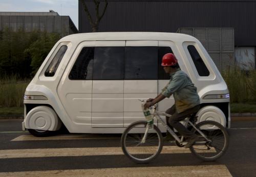 A worker rides a bike past a driverless vehicle at Vanke's Building Research Centre testing area in Dongguan