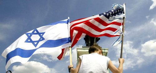 A boy holds a U.S. flag and Israeli flag during a demonstration in