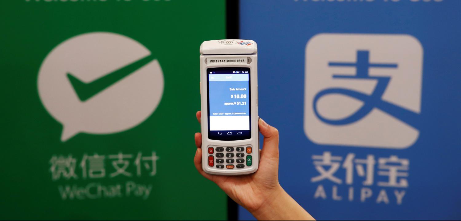 A woman demonstrates a high security digital unit built by Motion Pay, that allows customers to pay in Chinese yuan renminbi using Chinese online money payment services "WeChat Pay", and "Alipay", where payments get converted to Canadian dollars at point of sales locations in Canadian stores and businesses, in Toronto, Canada, May 24, 2017. This logo has been updated and is no longer in use. REUTERS/Mark Blinch - RC1C49693950