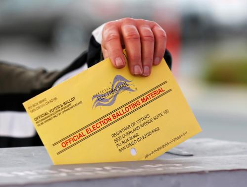 A poll worker places a mail in ballot into a voting box