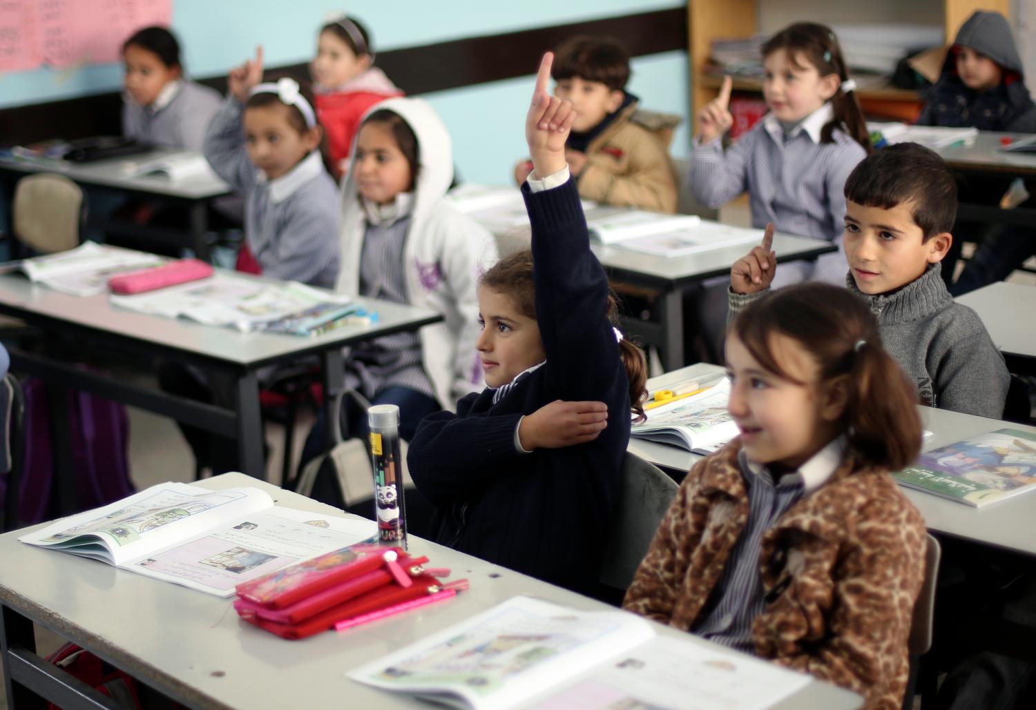 Palestinian first-graders sit with their schoolbook
