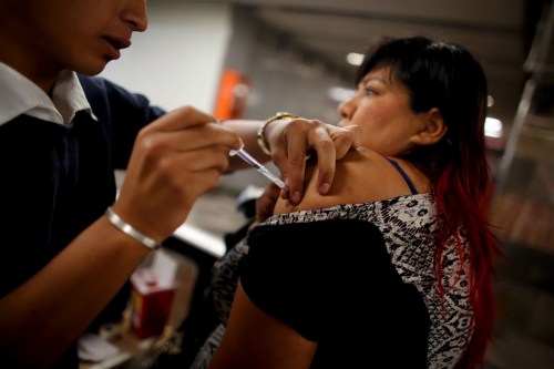 A woman receives a flu vaccination by injection for seasonal flu.