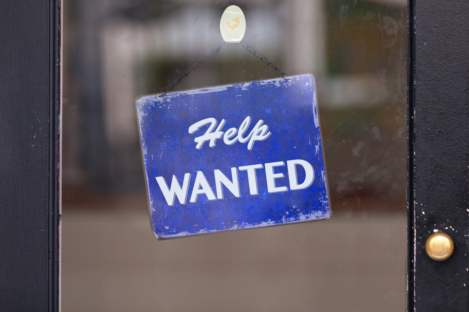Close-up on a blue help wanted sign.