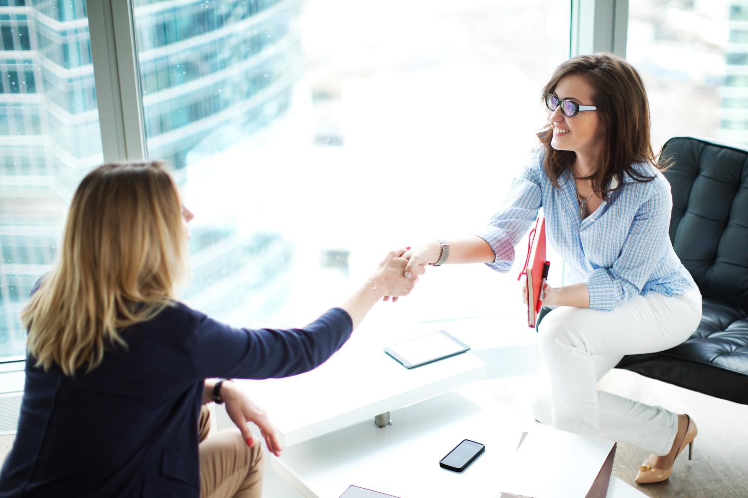 Job interview between two women shaking hands.