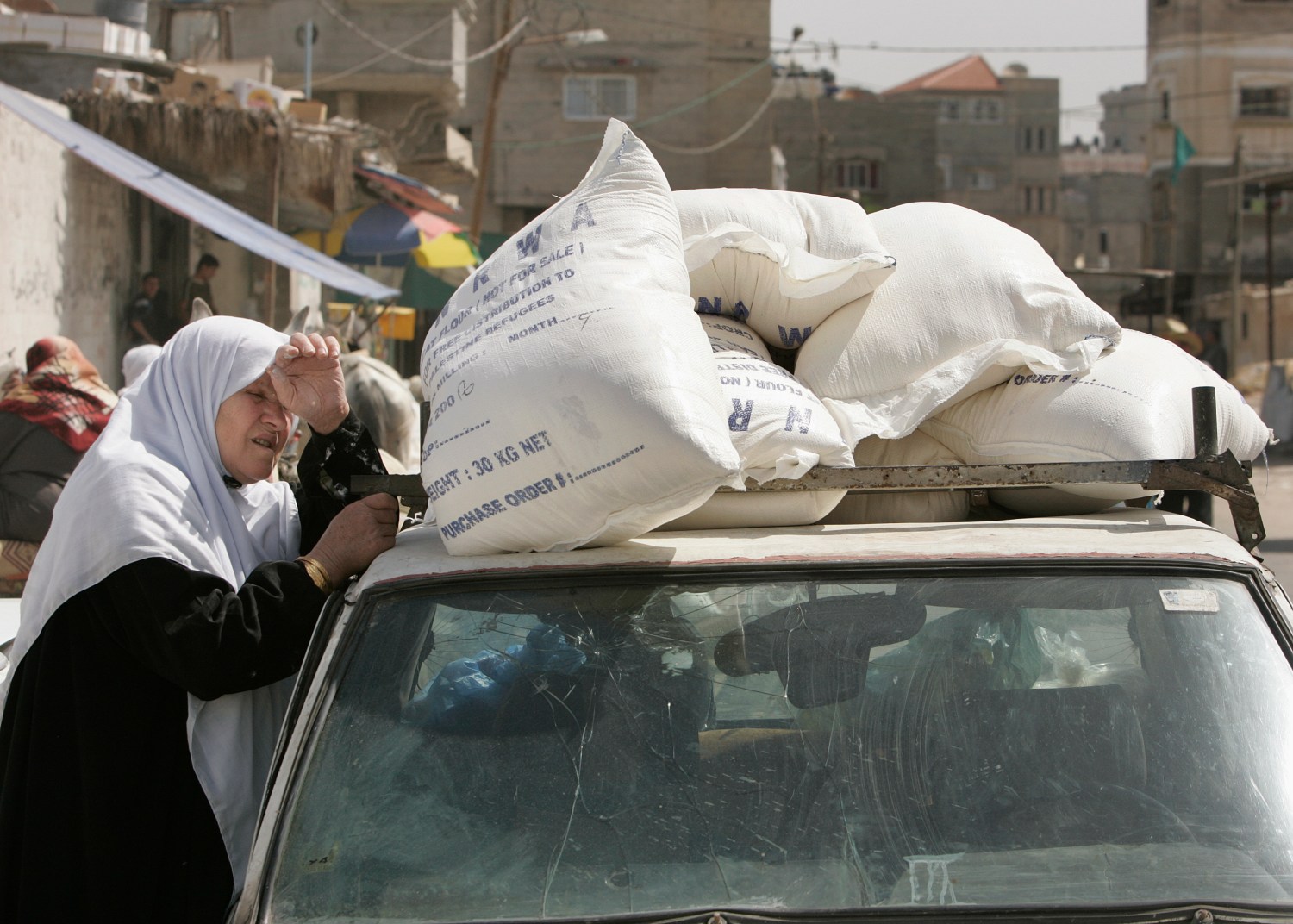 A Palestinian woman rests next to a car after receiving food supplies from the United Nations Works and Relief Agency (UNRWA) headquarters at the Shati refugee camp in Gaza May 5, 2008. The United Nations is set to halt delivery of humanitarian aid to the Gaza Strip on Monday because its vehicles have run out of fuel, a U.N. official said. REUTERS/Suhaib Salem (GAZA) -