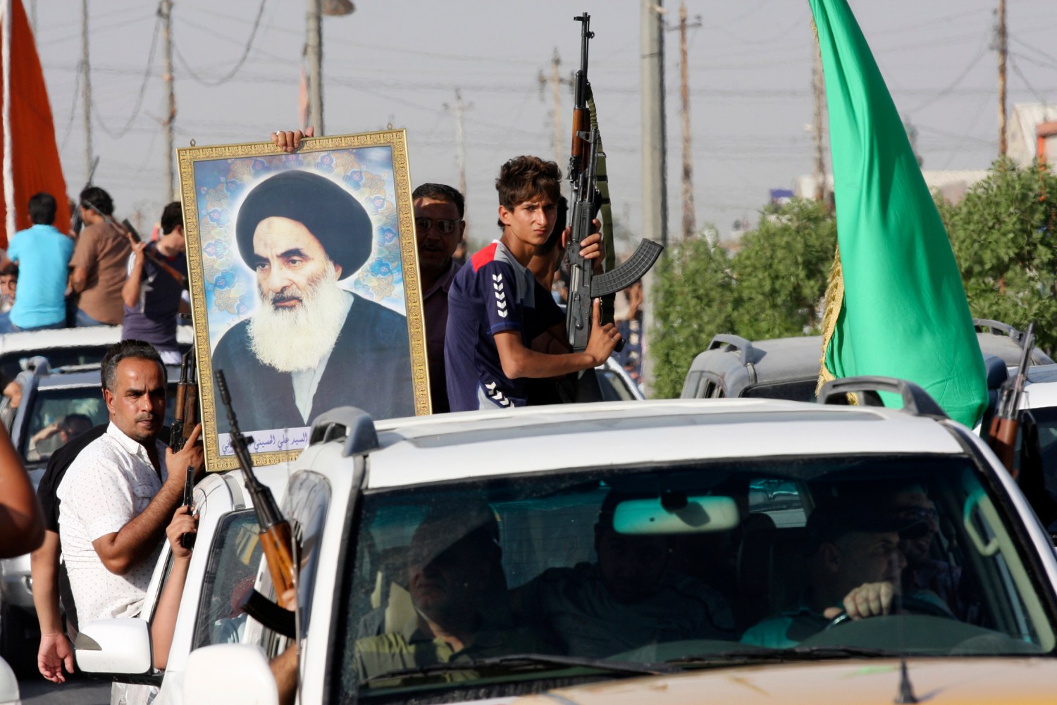 Volunteers, who have joined the Iraqi Army to fight against predominantly Sunni militants, carry weapons and a portrait of Grand Ayatollah Ali al-Sistani during a parade in the streets in Baghdad's Sadr city June 14, 2014. An offensive by insurgents that threatens to dismember Iraq seemed to slow on Saturday after days of lightning advances as government forces regained some territory in counter-attacks, easing pressure on the Shi'ite-led government in Baghdad. REUTERS/Wissm al-Okili