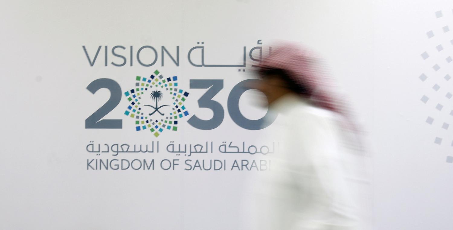 A man walks past the logo of Vision 2030 after a news conference, in Jeddah, Saudi Arabia June 7, 2016. REUTERS/Faisal Al Nasser/File Photo -