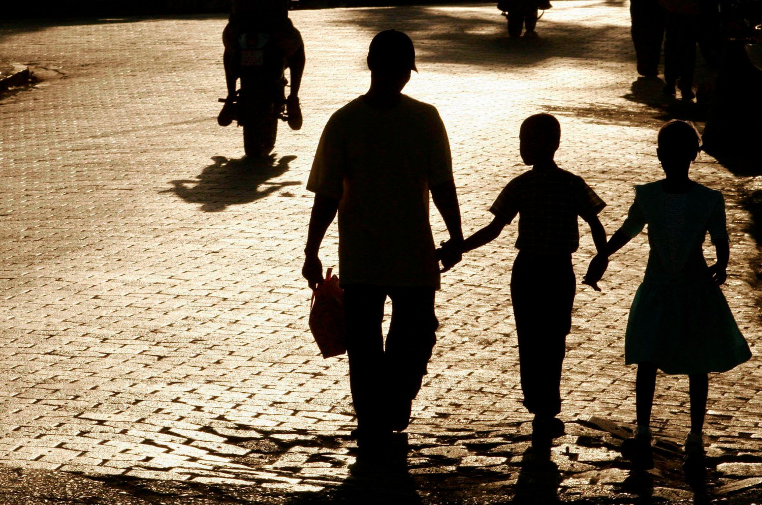 A shadowed family walks through a town.