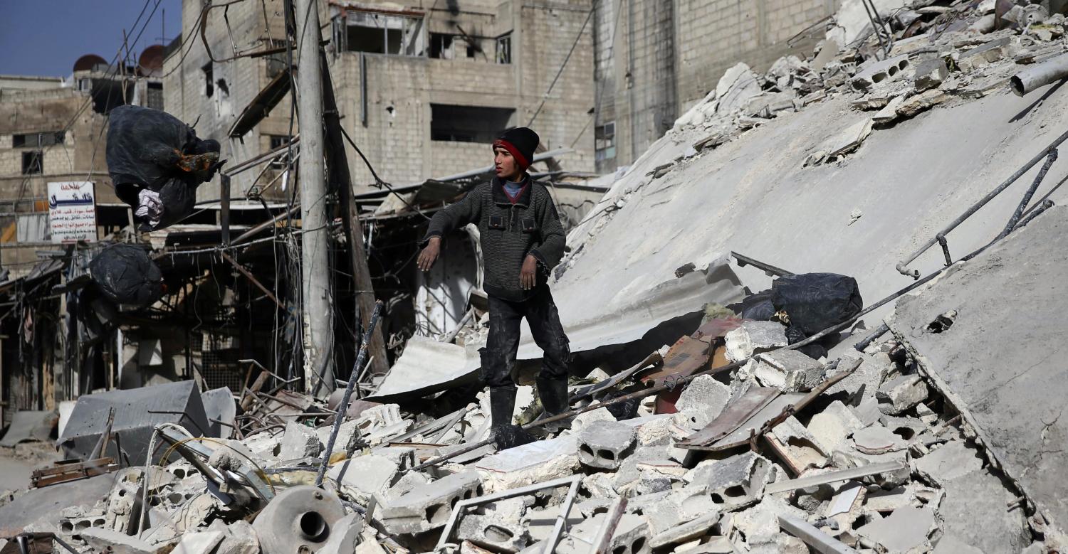 A boy stands on the rubble of a damaged building at the besieged town of Douma, Eastern Ghouta, Damascus, Syria March 5, 2018. REUTERS/Bassam Khabieh - RC123E639BD0