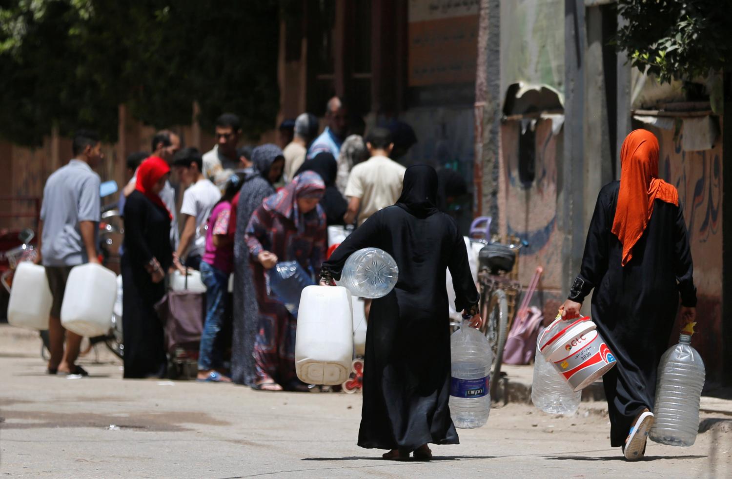 People line up with empty canisters and bottles as they wait to collect filtered water in Toukh, El-Kalubia governorate northeast of Cairo, Egypt June 30, 2017. REUTERS/Amr Abdallah Dalsh - RC15FDCAEB90