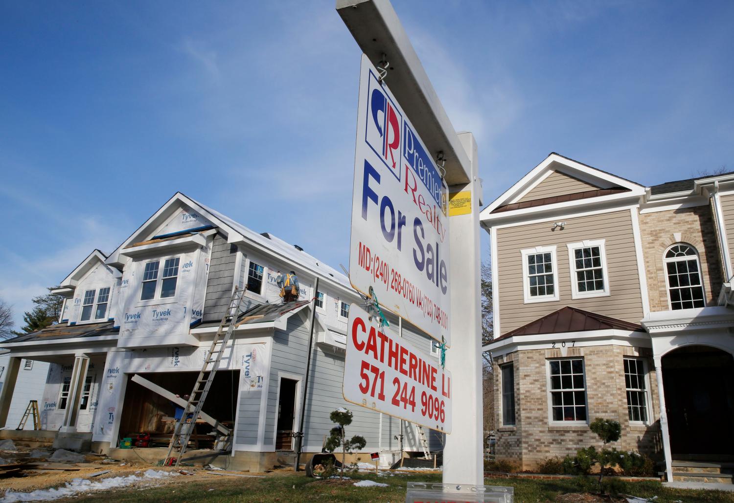 A new home is being built next to a home with a for sale sign.