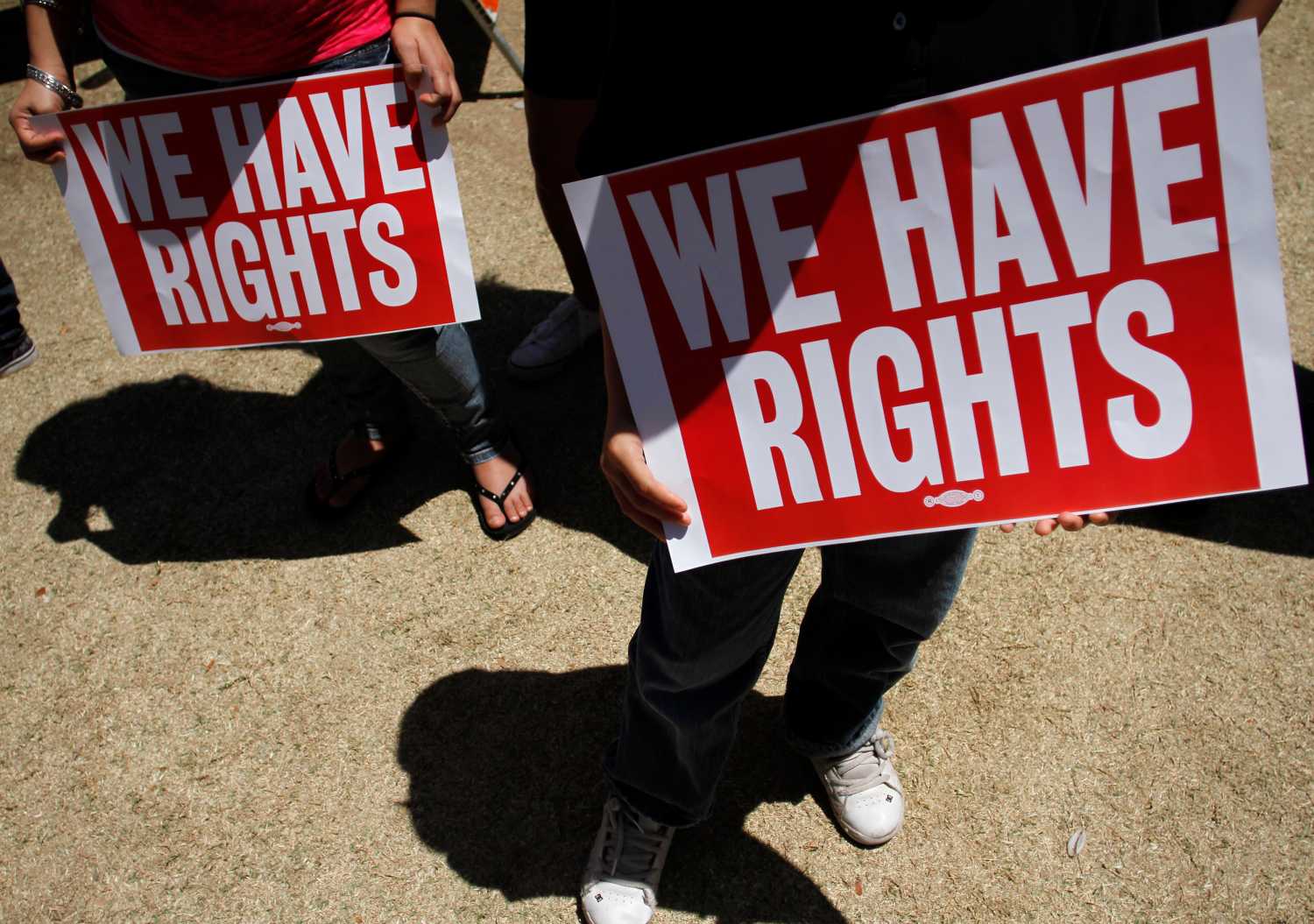 People hold signs as they protest against Senate Bill 1070 outside the Arizona State Capitol in Phoenix, Arizona April 25, 2010. Arizona's tough new immigration law has renewed calls for Washington to reform federal immigration laws, and protesters decried the state's action as a violation of U.S. civil rights at a rally on Sunday in the state's capital.