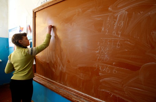 A child practices algebra on a chalk board.