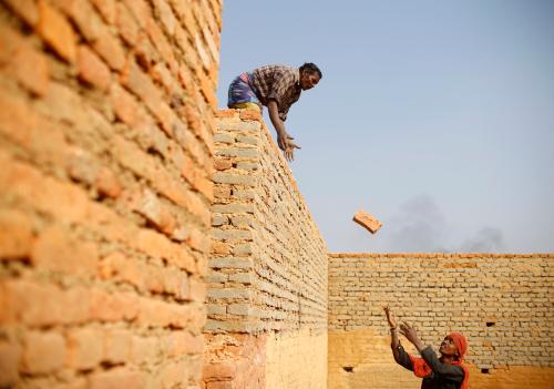 Indian migrant workers pass bricks at a brick factory in Lalitpur