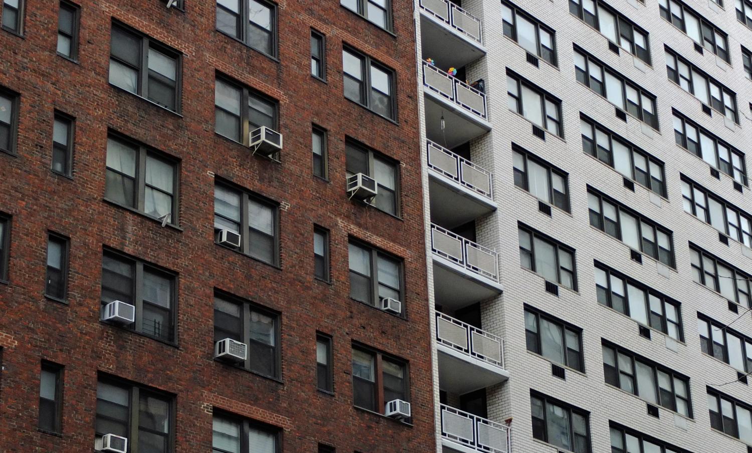 New York City apartment building exteriors, one white brick the other brown.