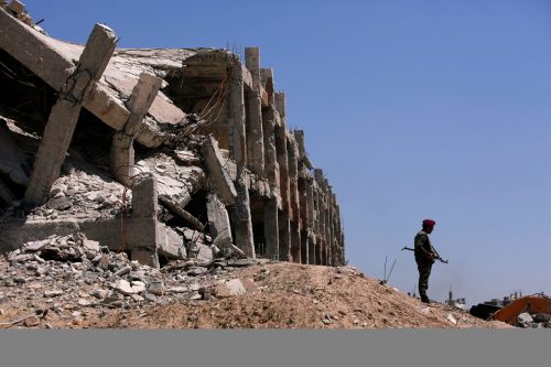 A member of Syrian forces of President Bashar al Assad stands guard near destroyed buildings in Jobar, eastern Ghouta, in Damascus, Syria April 2, 2018. REUTERS/Omar Sanadiki - RC12300737D0