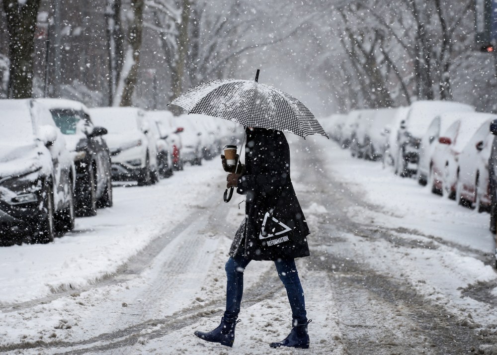 A woman walks in the snow during a winter nor'easter storm.
