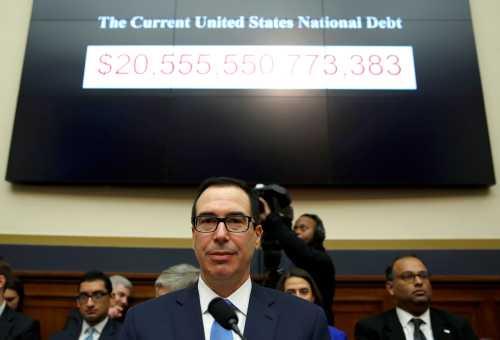 Treasury Secretary Steven Mnuchin sits under a display of the U.S. national debt.