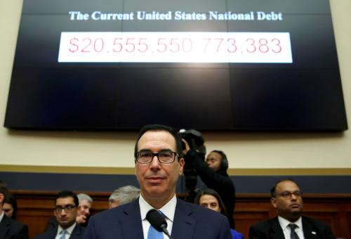Treasury Secretary Steven Mnuchin sits under a display of the U.S. national debt.