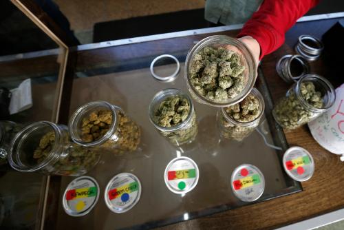 A volunteer displays jars of dried cannabis buds at the La Brea Collective medical marijuana dispensary in Los Angeles, California, March 18, 2014. The dispensary is on a list released by the city of over 100 stores that meet some of the requirements of a voter-approved measure.