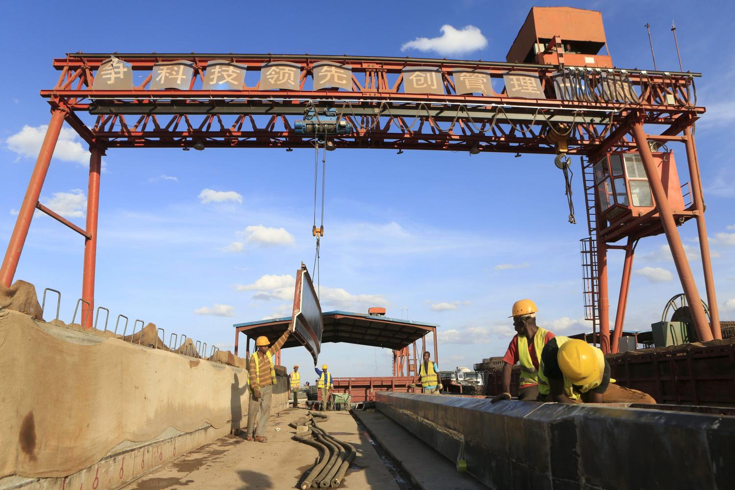 Workers are seen near a sign written in Chinese at the construction site of the Mombasa-Nairobi standard gauge railway at Emali