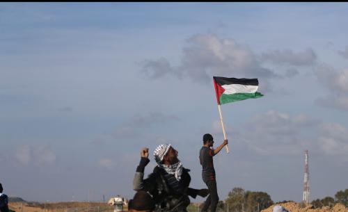 A demonstrator waves a Palestinian flag during clashes with Israeli troops at a protest against U.S. President Donald Trump's decision on Jerusalem, near the border with Israel in the southern Gaza Strip March 16, 2018. REUTERS/Ibraheem Abu Mustafa - RC1D250522B0