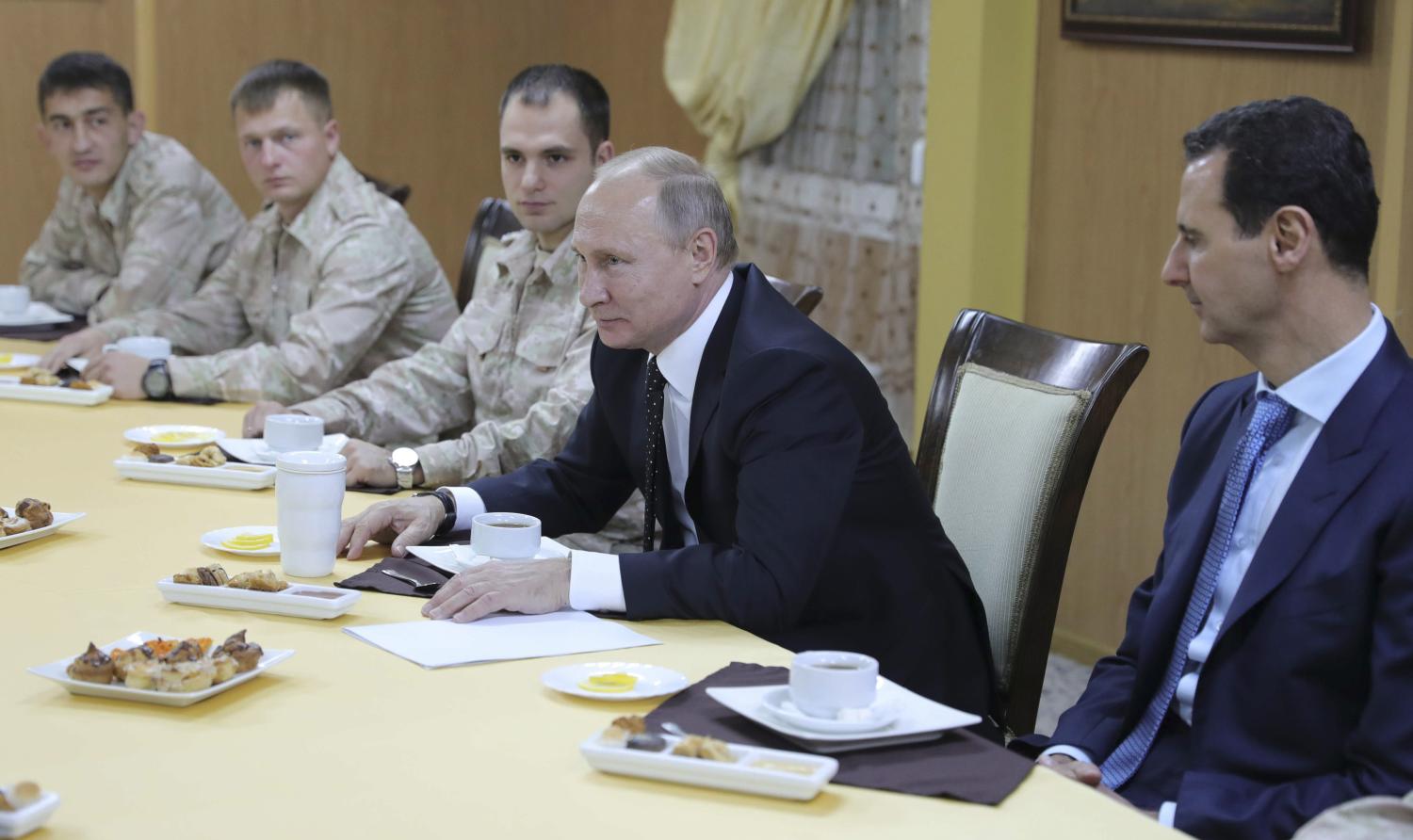 Russian President Vladimir Putin (2nd R) and Syrian President Bashar al-Assad (R) meet with servicemen as they visit the Hmeymim air base in Latakia Province, Syria December 11, 2017. Sputnik/Mikhail Klimentyev/Sputnik via REUTERS ATTENTION EDITORS - THIS IMAGE WAS PROVIDED BY A THIRD PARTY. - UP1EDCB13BY37