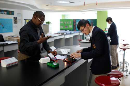 Uniformed student performs a science experiment next to a professor.