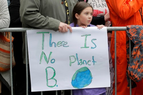 A girl holds a sign saying There is no planet B.