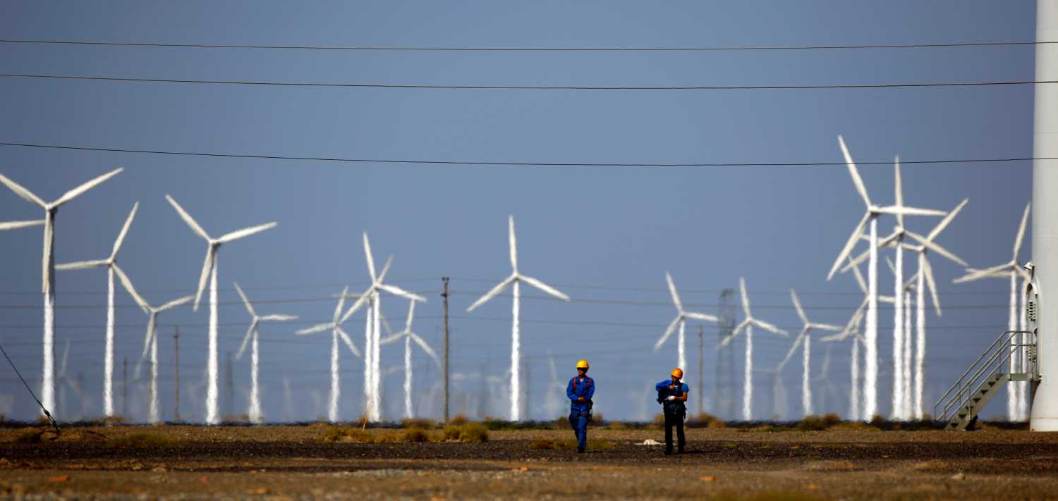 Workers walk near wind turbines for generating electricity, at a wind farm in Guazhou, 950km northwest of Lanzhou, Gansu Province