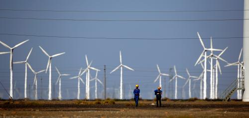 Workers walk near wind turbines for generating electricity, at a wind farm in Guazhou, 950km northwest of Lanzhou, Gansu Province