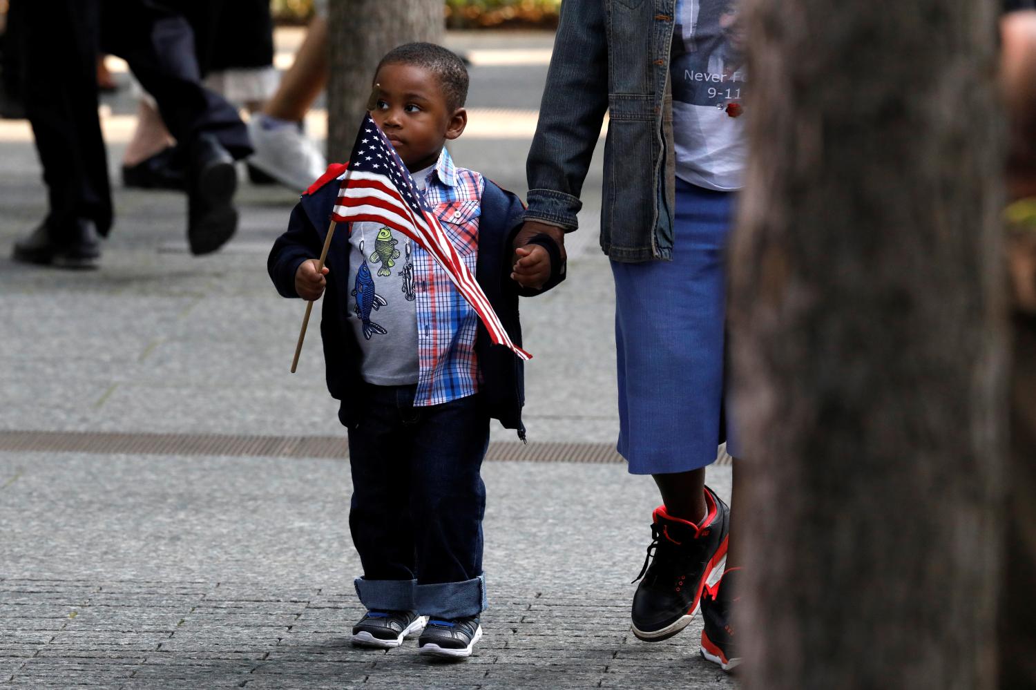 A young boy of color carries an American flag