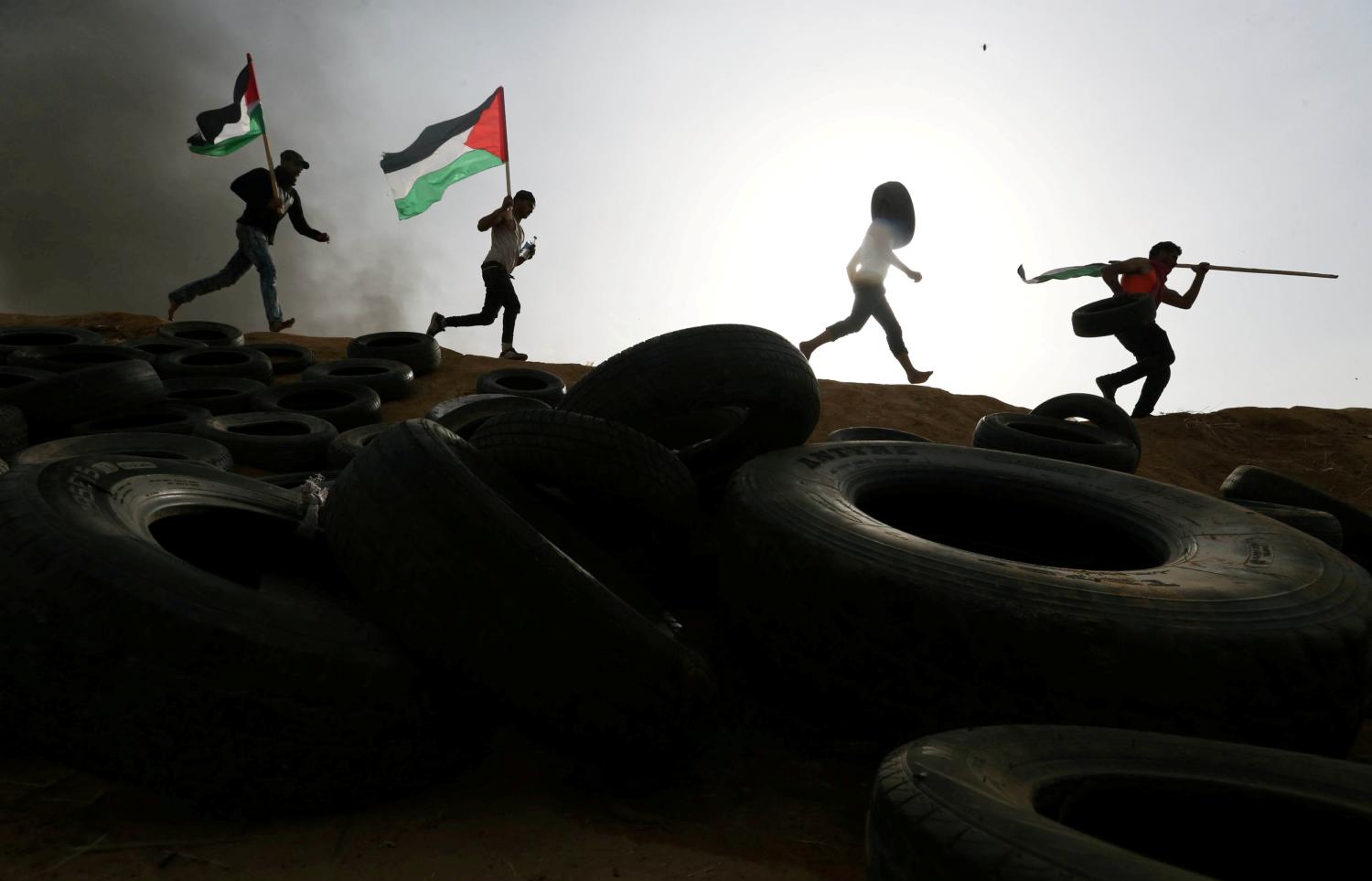 Palestinian protesters run during clashes with Israeli troops at Israel-Gaza border, in the southern Gaza Strip April 5, 2018. REUTERS/Ibraheem Abu Mustafa