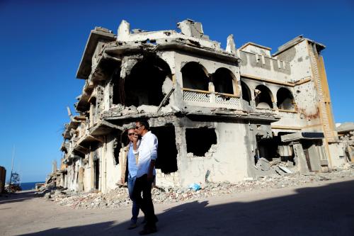 Men walk past the ruins of a building that was destroyed during clashes between Libyan forces and Islamic State militants, in Sirte, Libya, November 1, 2017. Picture taken November 1, 2017. REUTERS/Ahmed Jadallah - RC16BEF8E700