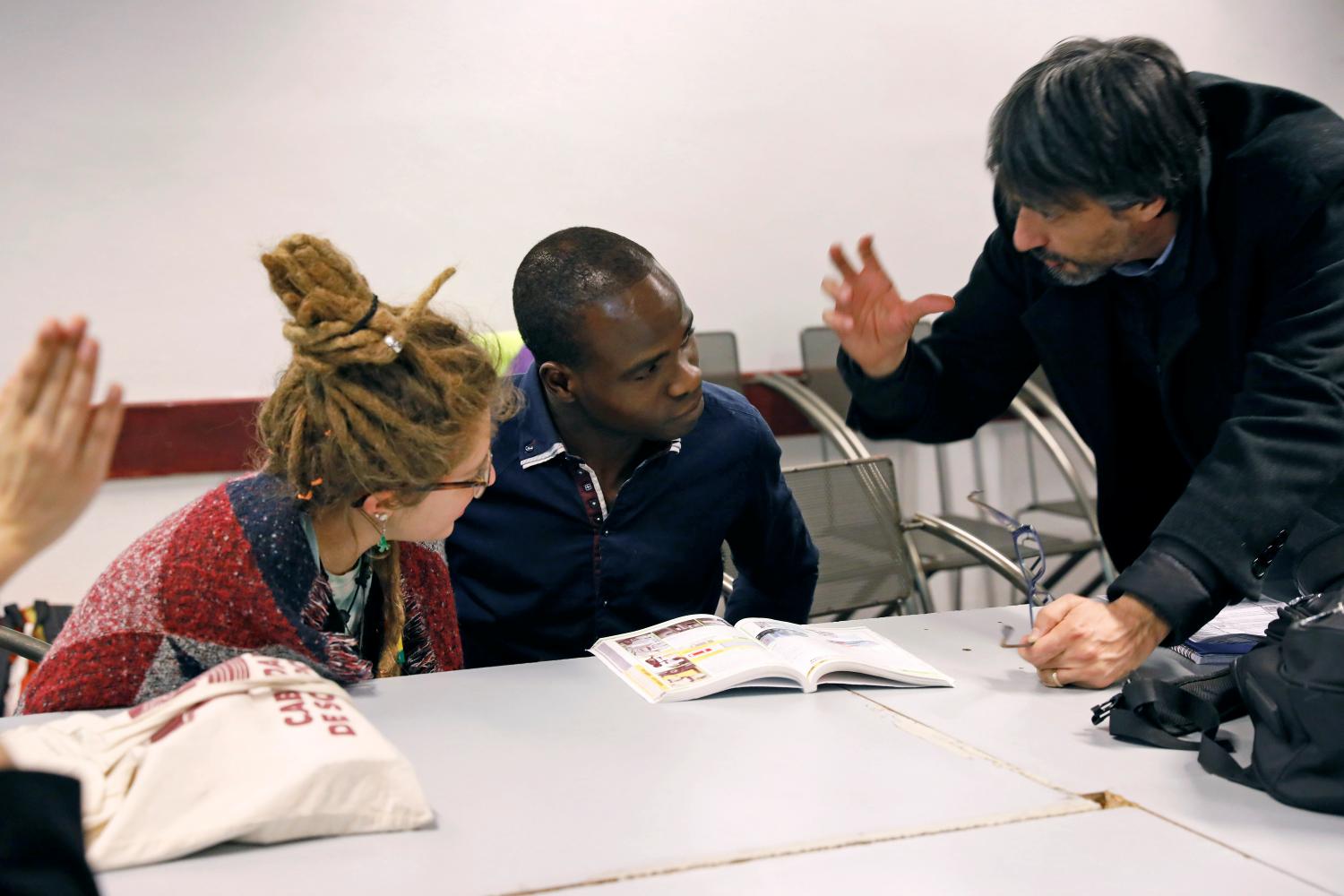 A migrant converses with a teacher during Italian language classes near the former Olympic village in Turin