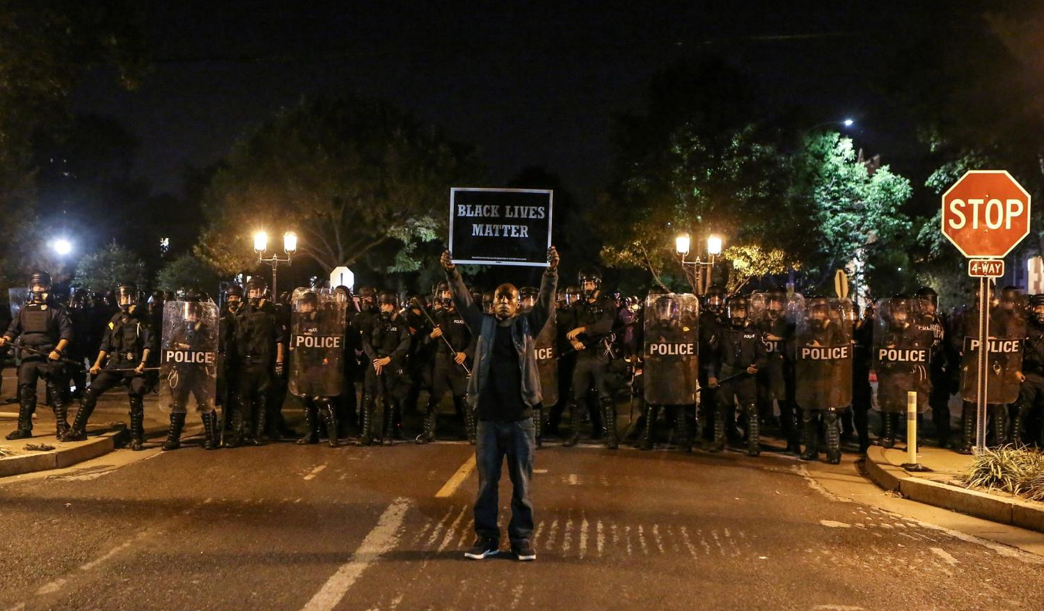 A Black Lives Matter protester stands in front of St. Louis Police Department officers equipped with riot gear after the not guilty verdict in the murder trial of Jason Stockley, a former St. Louis police officer, charged with the 2011 shooting of  Anthony Lamar Smith, who was black, in St. Louis, Missouri, U.S., September 15, 2017.  Photo taken September 15, 2017.  REUTERS/Lawrence Bryant     TPX IMAGES OF THE DAY - RC162B2292E0