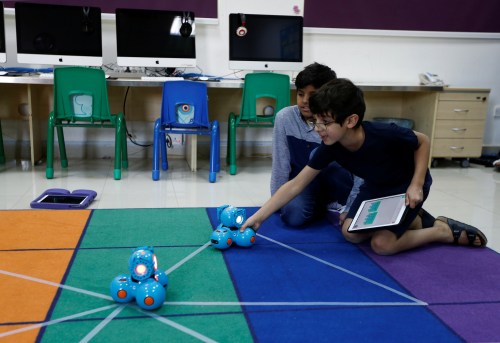 Boys attend a computer programming lesson using robots connected with an application as part of Kcoderz social initiative