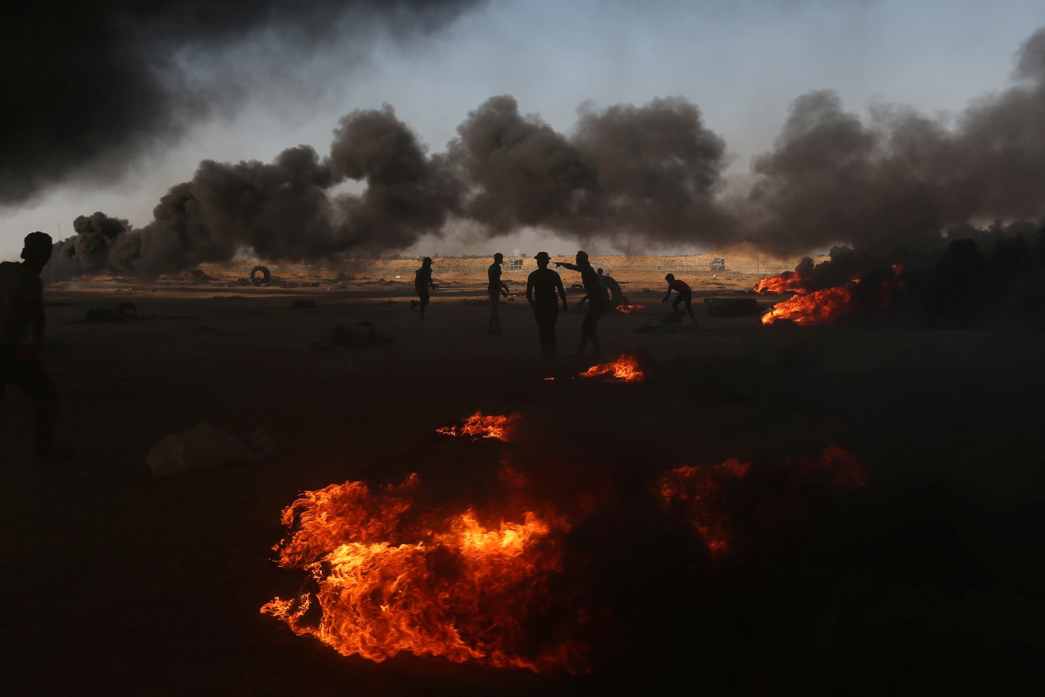 Palestinian demonstrators are seen as smoke rises from burning tires during a protest marking the 70th anniversary of Nakba, at the Israel-Gaza border in the southern Gaza Strip May 15, 2018. REUTERS/Ibraheem Abu Mustafa     TPX IMAGES OF THE DAY - RC164F7FC530