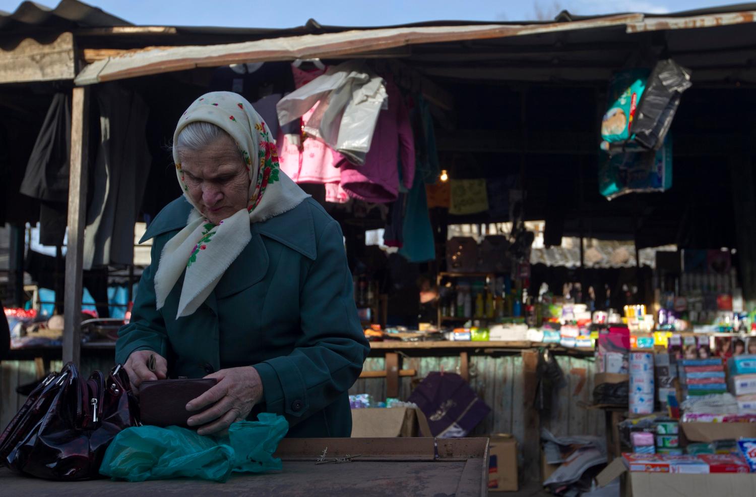An elderly woman counts money at a market in the town of Tkvarcheli, some 50 km (31 miles) southeast of Sukhumi, the capital of Georgia's breakaway region of Abkhazia December 27, 2013. The territory of Abkhazia is located several miles southwest of the border with Russia and the Olympic Park in the Adler district of the Black Sea resort city of Sochi which will host the 2014 Winter Olympic Games in February. Abkhaz separatists fought Georgian government forces in 1992-1993, after which the breakaway region declared independence. Russia, Nicaragua, Venezuela, Nauru, Vanuatu and Tuvalu recognized Abkhazia as an independent state while all other countries regard it as a Georgian province, according to local media. Picture taken December 27, 2013. REUTERS/Maxim Shemetov (GEORGIA  - Tags: SOCIETY POLITICS OLYMPICS SPORT) - GM1EA161B4D01