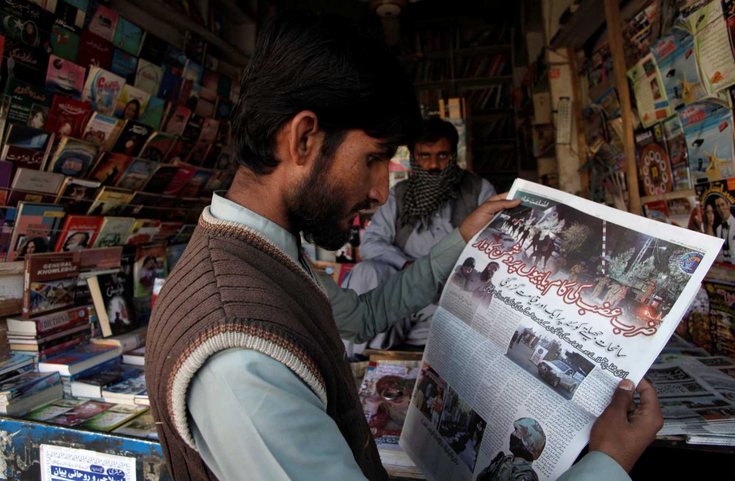 A man reads a newspaper's coverage of the attack on the Police Training College, at a newsstand in Quetta, Pakistan, October 26, 2016. REUTERS/Naseer Ahmed - S1AEUJDWITAA