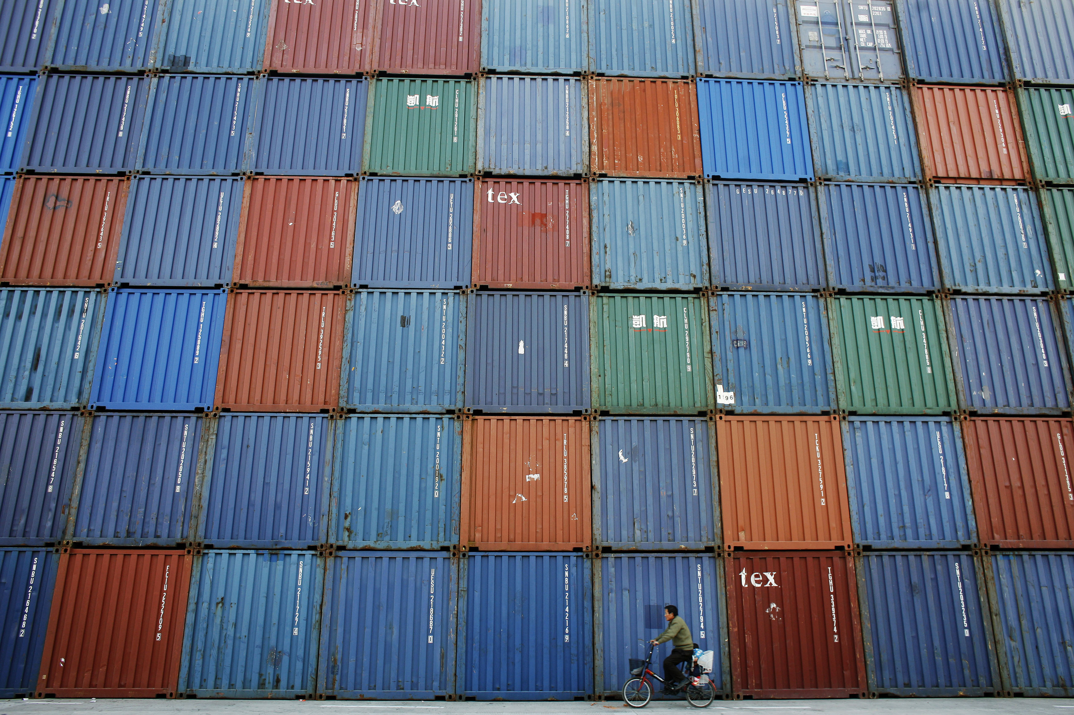 A man rides a bicycle past containers at a port in Shanghai in this December 10, 2008 file picture. Seemingly effortlessly, China has amassed the world's biggest stockpile of foreign exchange reserves, is overtaking Germany as the biggest exporting nation and now has a car market bigger than America's. Picture taken December 10, 2008. To match Special Report DAVOS/CHINA-GROWTH REUTERS/Aly Song/Files (CHINA - Tags: BUSINESS) - GM1E61K0PTG01