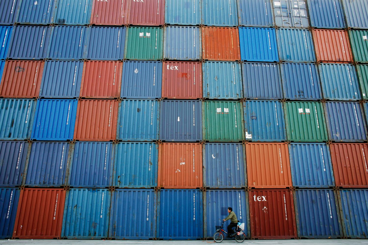 A man rides a bicycle past containers at a port in Shanghai in this December 10, 2008 file picture. Seemingly effortlessly, China has amassed the world's biggest stockpile of foreign exchange reserves, is overtaking Germany as the biggest exporting nation and now has a car market bigger than America's. Picture taken December 10, 2008. To match Special Report DAVOS/CHINA-GROWTH REUTERS/Aly Song/Files (CHINA - Tags: BUSINESS) - GM1E61K0PTG01