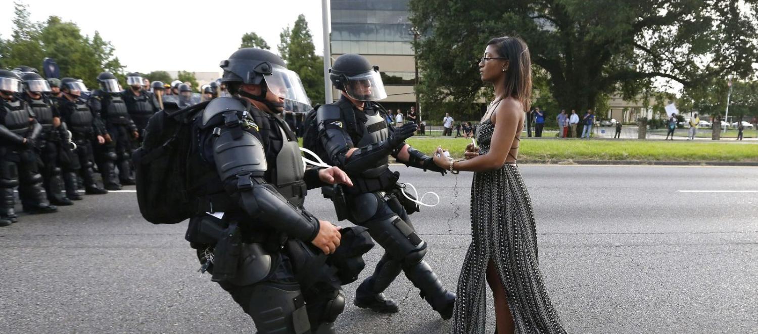 Lone activist Ieshia Evans stands her ground while offering her hands for arrest as she is charged by riot police during a protest against police brutality outside the Baton Rouge Police Department in Louisiana, USA, 9 July 2016. Evans, a 28-year-old Pennsylvania nurse and mother of one, traveled to Baton Rouge to protest against the shooting of Alton Sterling. Sterling was a 37-year-old black man and father of five, who was shot at close range by two white police officers. The shooting, captured on a multitude of cell phone videos, aggravated the unrest coursing through the United States in previous years over the use of excessive force by police, particularly against black men. REUTERS/Jonathan Bachman   TPX IMAGES OF THE DAY - RC1F5C88B300