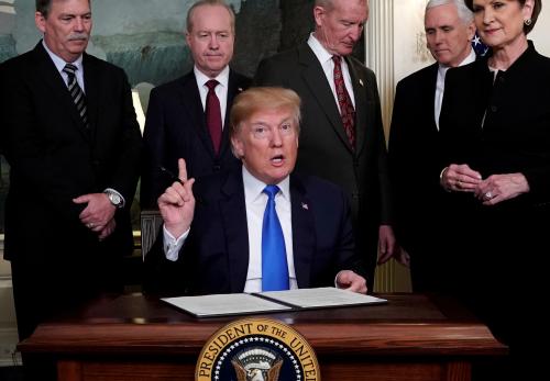 U.S. President Donald Trump, surrounded by business leaders and administration officials, prepares to sign a memorandum on intellectual property tariffs on high-tech goods from China, at the White House in Washington, U.S. March 22, 2018. REUTERS/Jonathan Ernst