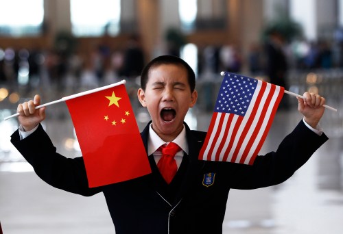A boy who is waiting to greet U.S. Secretary of State Hillary Clinton at the National Museum makes a face while holding the U.S. and Chinese flags in Beijing May 4, 2012.  REUTERS/Shannon Stapleton (CHINA - Tags: POLITICS BUSINESS TPX IMAGES OF THE DAY) - GM1E8541BEV01