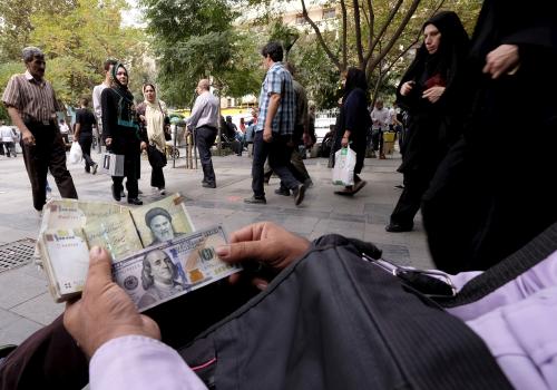A money changer displays U.S. and Iranian banknotes at the Grand Bazaar in central Tehran October 7, 2015. To match Insight IRAN-BANKING/  REUTERS/Raheb Homavandi/TIMA/File Photo ATTENTION EDITORS - THIS IMAGE WAS PROVIDED BY A THIRD PARTY. EDITORIAL USE ONLY. - S1BETSJMVNAC