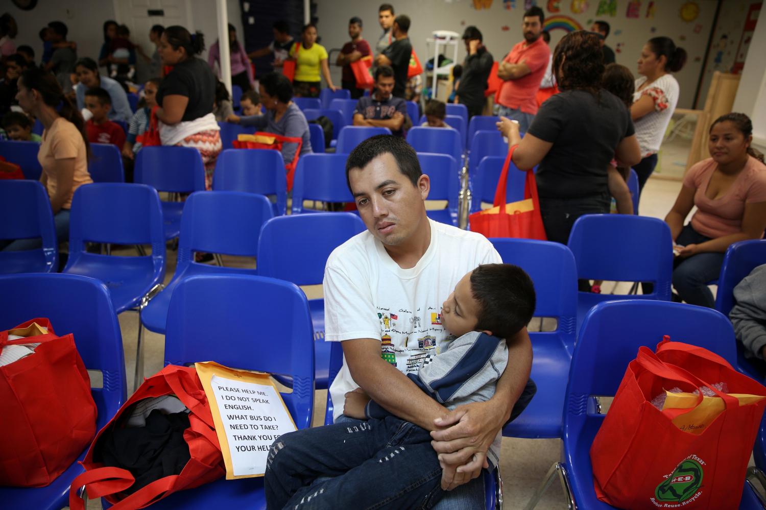 An undocumented immigrant from Honduras and his son, recently released from detention through "catch and release" immigration policy, pass the time before beginning a bus journey to Louisiana at the Catholic Charities relief center in McAllen, Texas, U.S., April 6, 2018.  REUTERS/Loren Elliott - RC1B544F5750