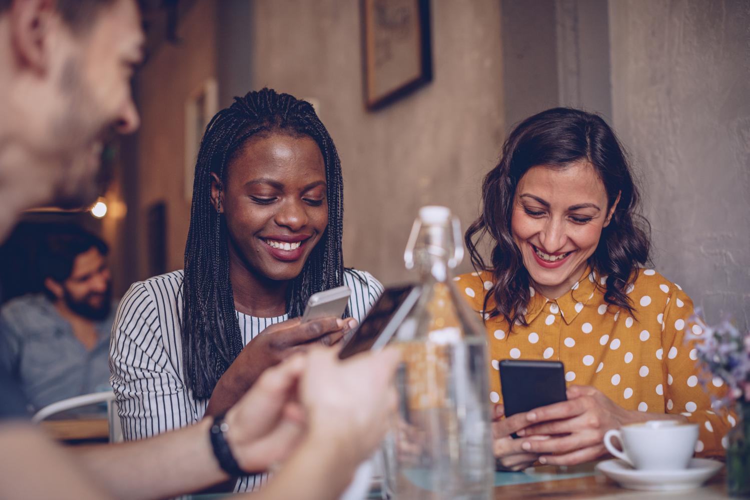 Friends at coffee shop using phones