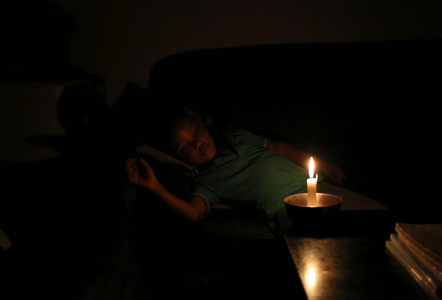 A child rests while illuminated by candle light during a scheduled blackout in South Africa